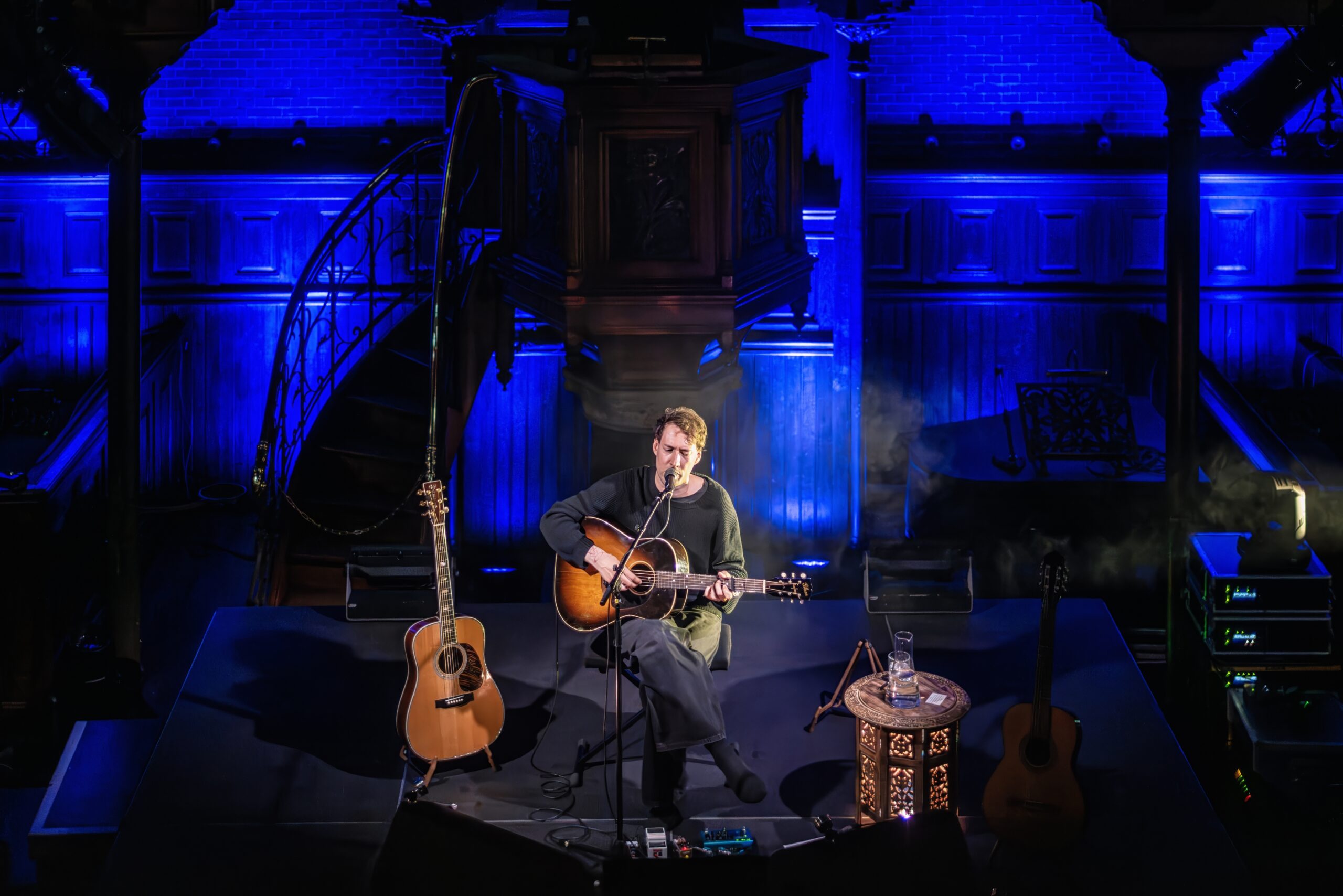 Eloi Youssef gezeten op een kruk, blauw belicht tegen het orgel van Arminius